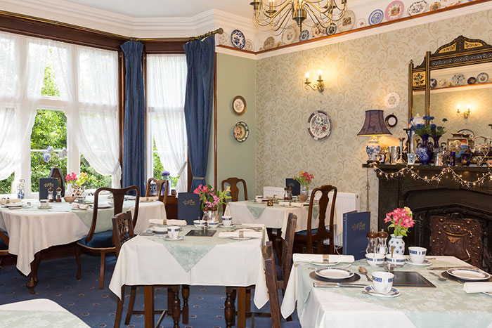 The breakfast room at The Old Vicarage, laid with white linen and blue china