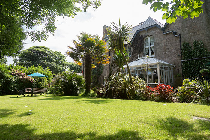 The Old Vicarage and its conservatory viewed from the sunlit lawn