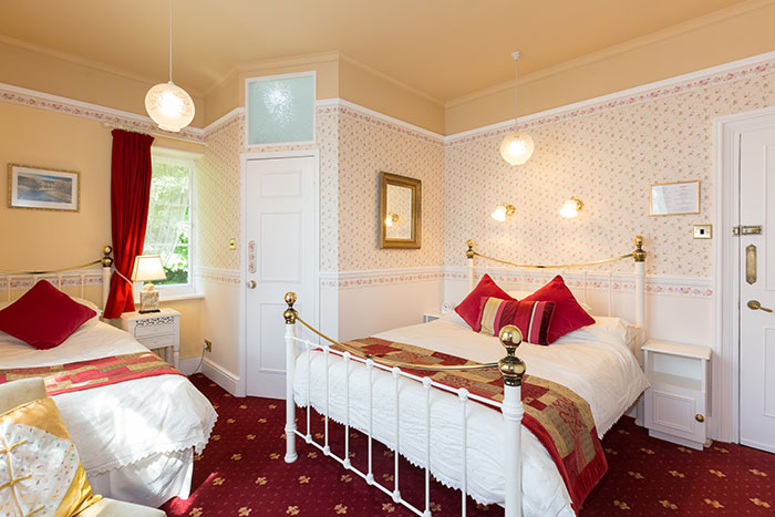 En-suite bedroom at The Old Vicarage with brass bedstead and floral wallpaper