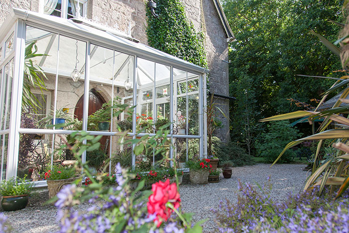 The glazed conservatory set against the granite and ivy of the old vicarage
